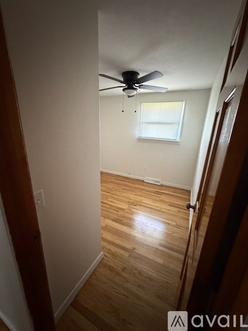 A room with a ceiling fan and wooden floors.