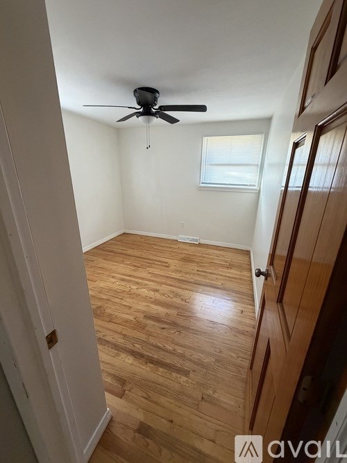 A room with a ceiling fan and wooden flooring.