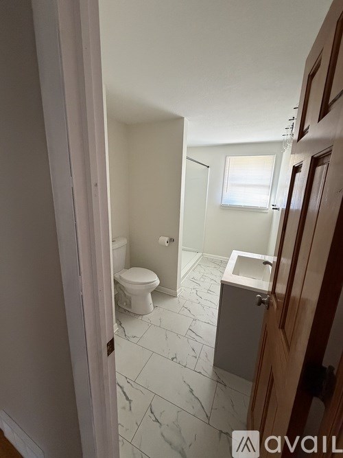 A bathroom with a toilet, sink and marble tiles.