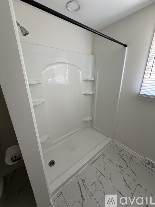 A white shower stall with a glass door and a black handle.