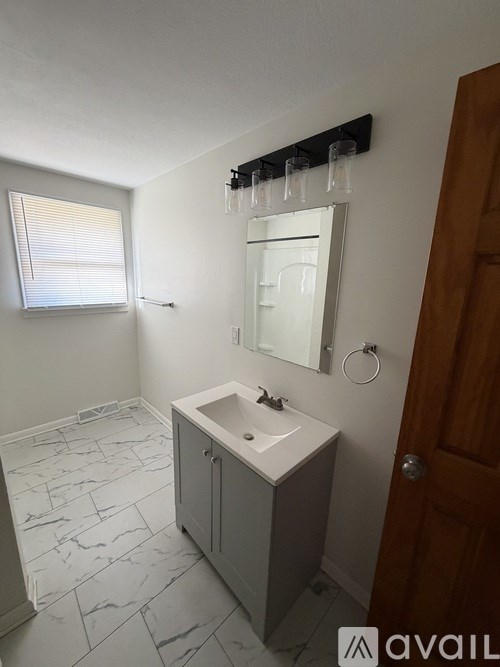 A bathroom with a sink, mirror, and tiled floor.