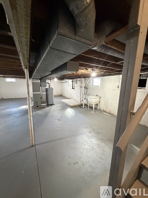 A room with a concrete floor and a ceiling with exposed beams.