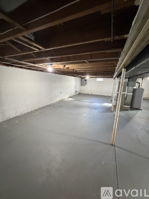 A spacious attic with wooden beams and a concrete floor.