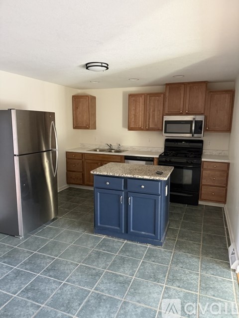 A kitchen with a blue island and stainless steel appliances.