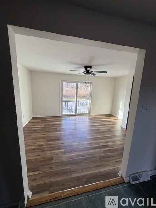A room with wooden flooring and a ceiling fan.