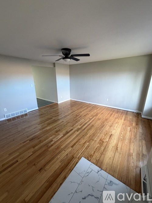 A room with wooden flooring and a ceiling fan.