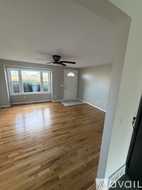 A room with wooden flooring and a ceiling fan.