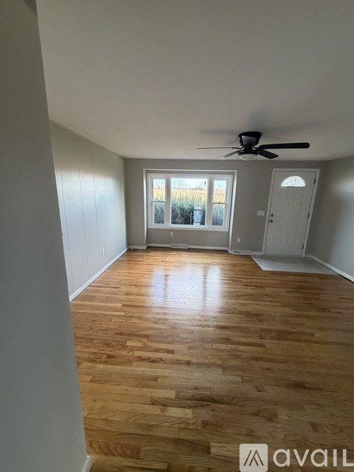 A room with wooden flooring and a ceiling fan.