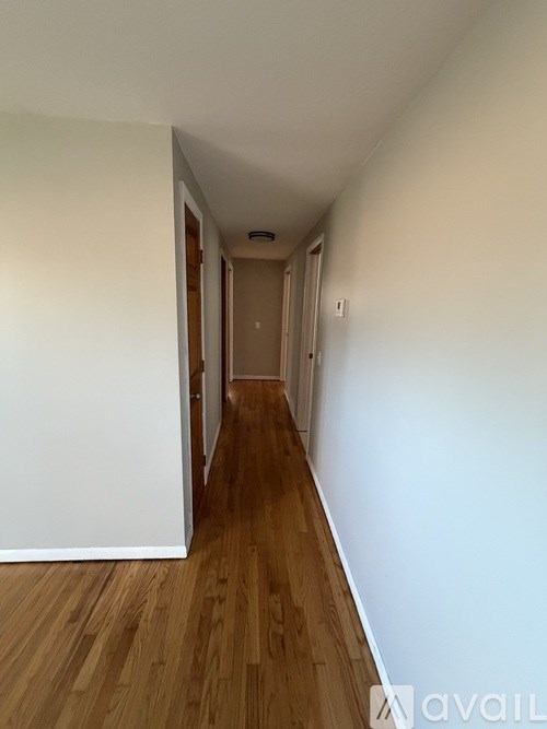 A long hallway with wooden floors and white walls.
