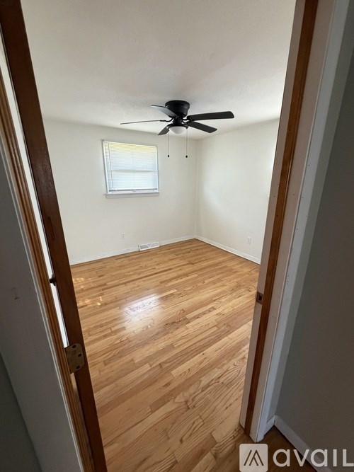 A room with wooden flooring and a ceiling fan.