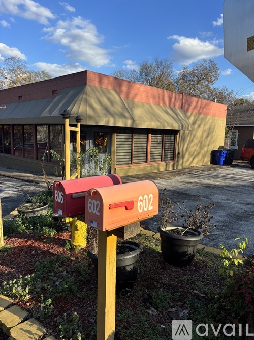 A red mailbox with the number 602 on it is in front of a building.