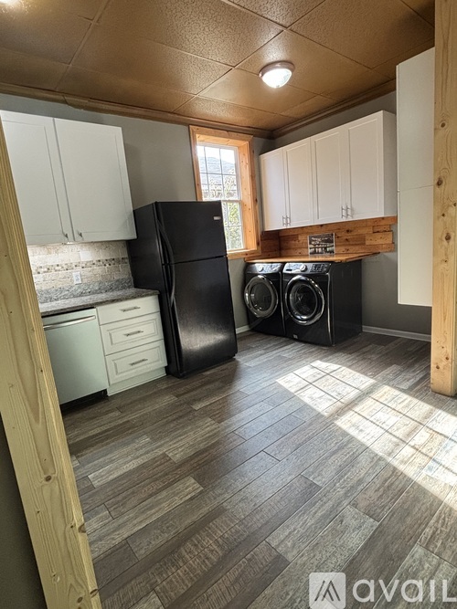 A kitchen with a black refrigerator and a black washing machine.