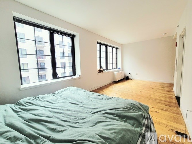 A bedroom with a bed and a window overlooking a cityscape.