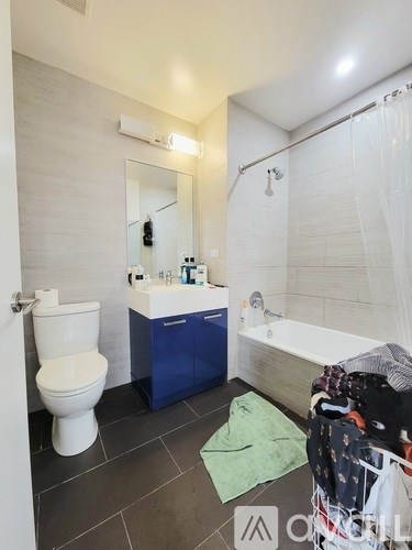 A bathroom with a white toilet, a blue sink, and a white bathtub.