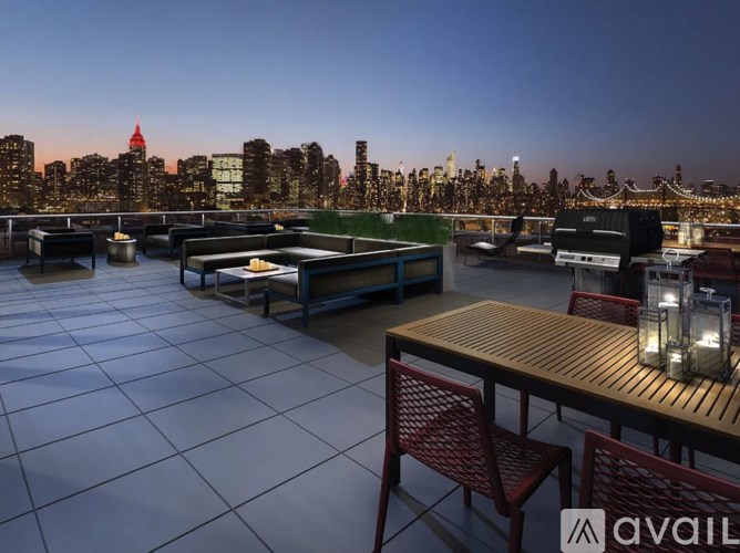 A rooftop patio with a table and chairs overlooking a city skyline at dusk.