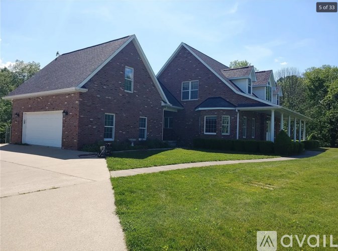 A two-story brick house with a garage on the left and a covered porch on the right.