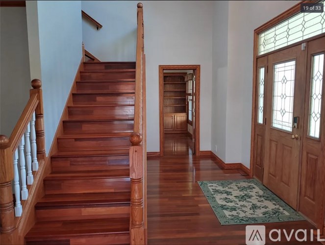 A wooden staircase with a green rug on the floor.