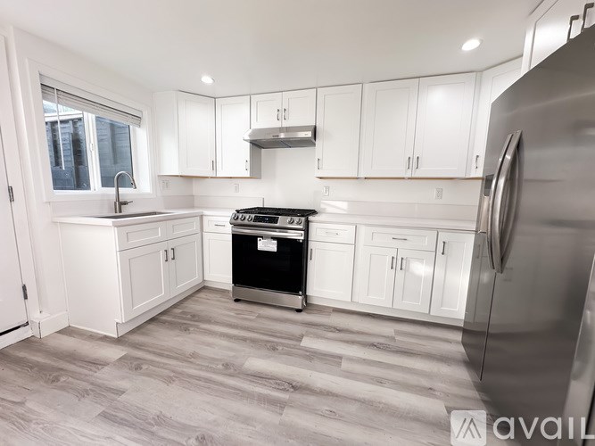 A modern kitchen with white cabinets and a stainless steel refrigerator.