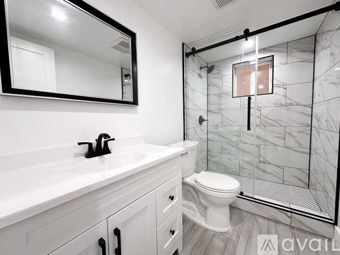 A bathroom with a marble tile shower and a white toilet.