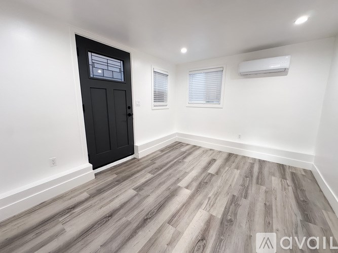 A room with a black door and wooden flooring.