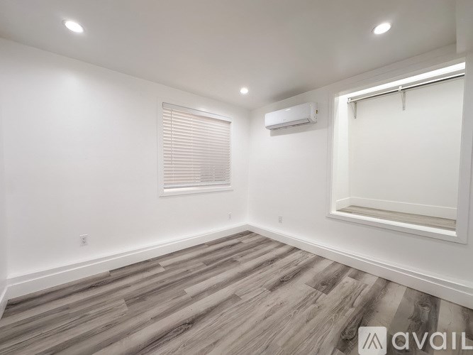 A room with wooden flooring and a window with blinds.