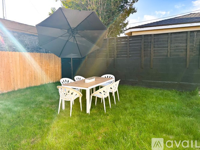 A table with chairs and an umbrella in a backyard.