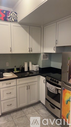 A kitchen with white cabinets and a black countertop.