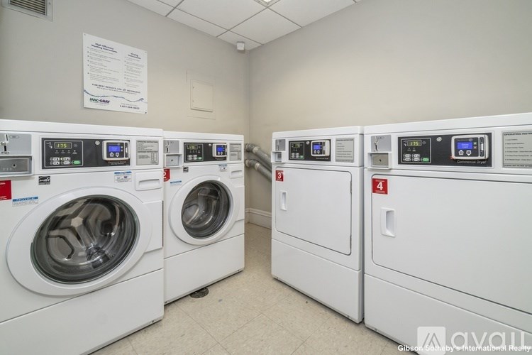 A row of white front load washing machines in a laundry room.