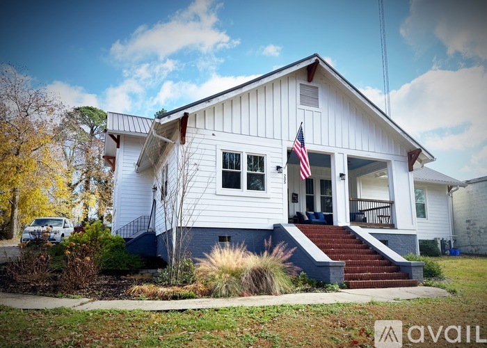 A white house with a blue trim and an American flag on the front porch.