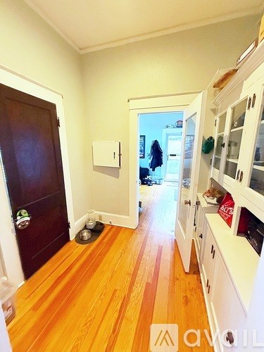 A kitchen with white cabinets and a wooden floor.