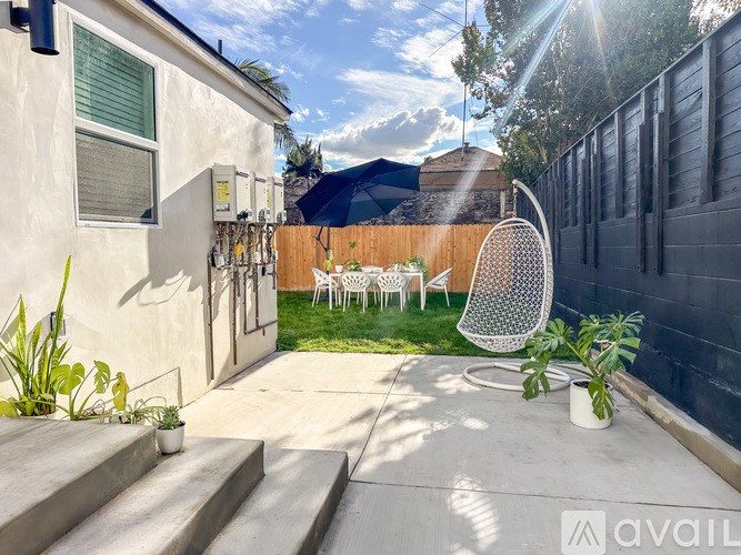 A sunny backyard with a patio, chairs, and plants.