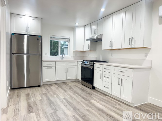 A kitchen with white cabinets and a stainless steel refrigerator.