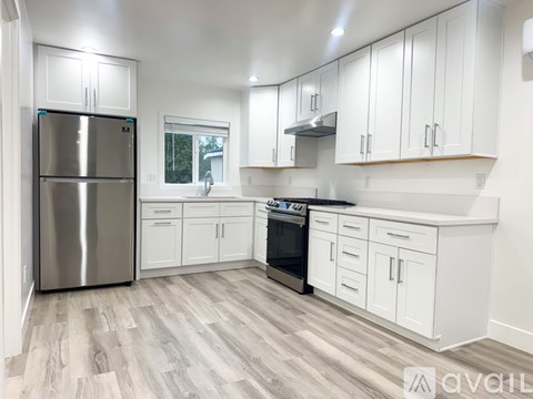 A kitchen with white cabinets and a stainless steel refrigerator.