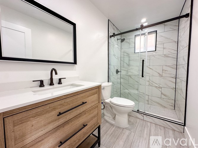 A bathroom with a toilet, sink, and a glass shower stall.