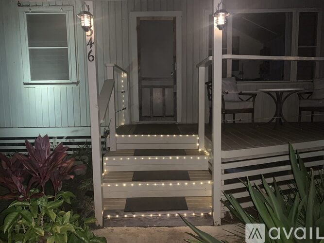 A white building with a staircase leading to the door.