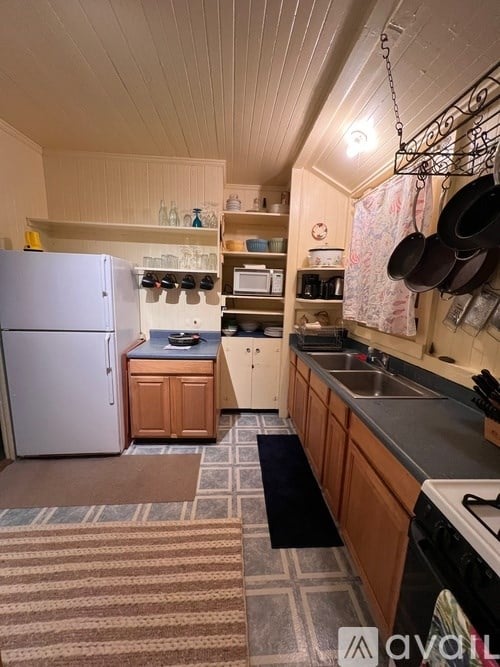 A small kitchen with a refrigerator, sink, and wooden cabinets.