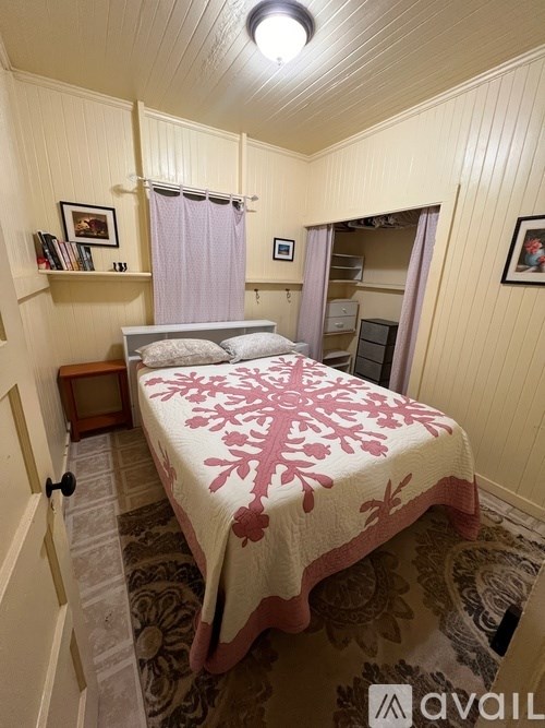 A bedroom with a bed covered in a pink and white comforter.