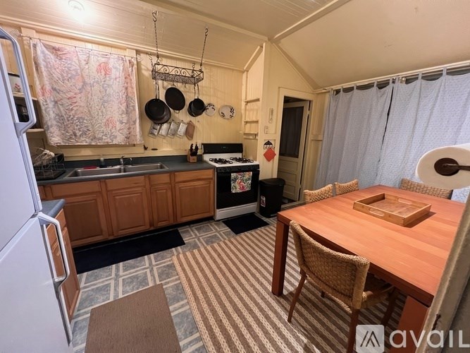 A kitchen with a refrigerator, a table with chairs, and a counter with a sink.