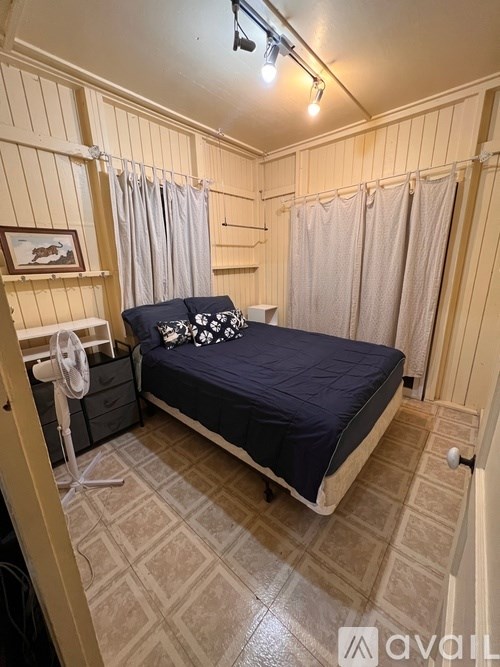 A bedroom with a bed, nightstand, and a fan.