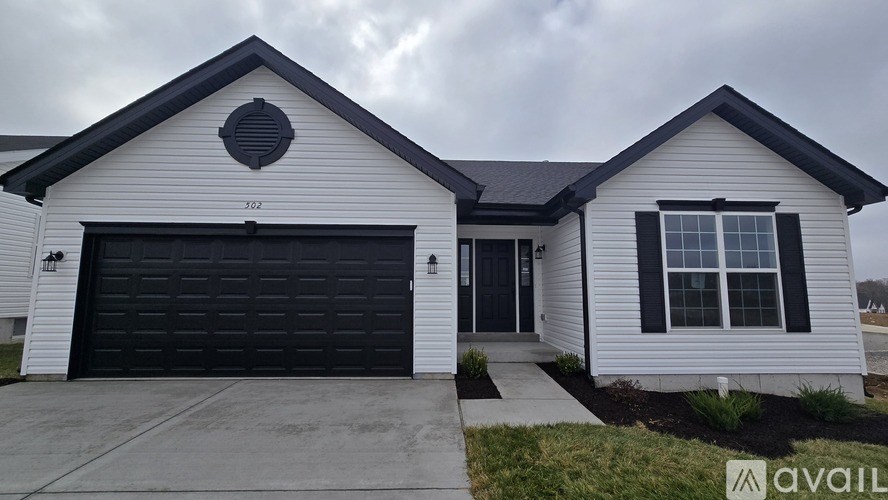 A two-story house with a black garage door and a white exterior.