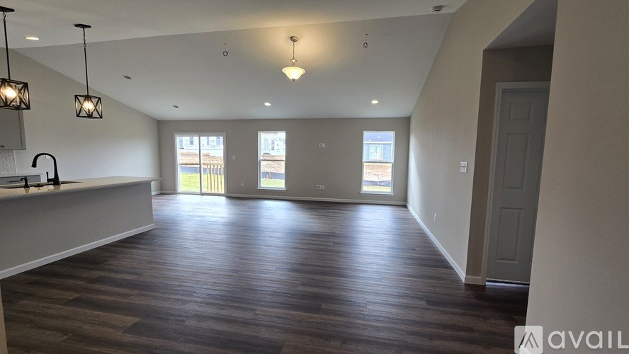 A spacious room with wooden floors and a bar area.