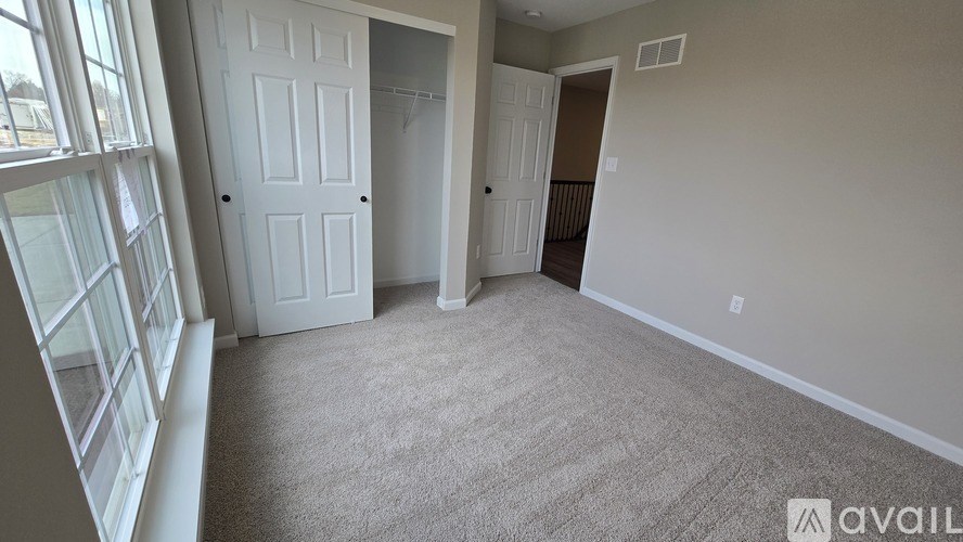 A room with a carpeted floor and two white doors.