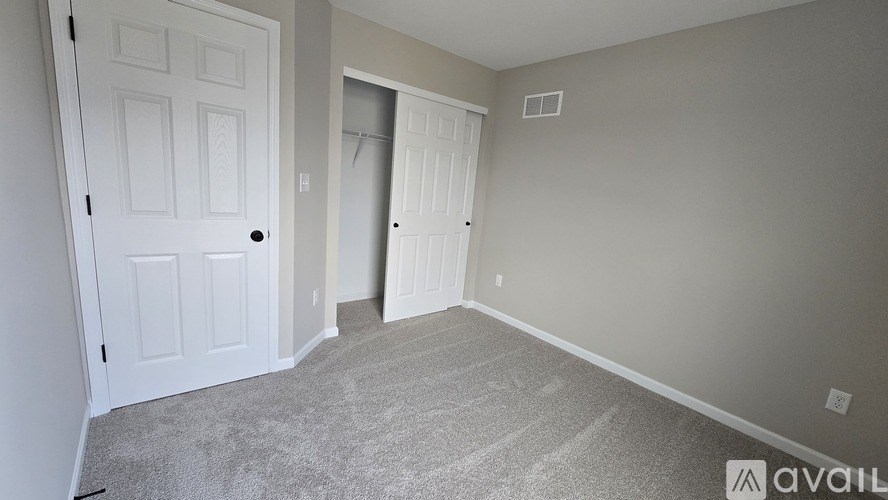 A room with a carpeted floor and two doors.
