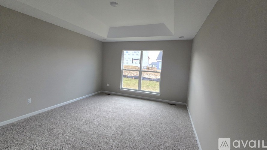 A room with a carpeted floor and a window showing a view of a building and a tree.