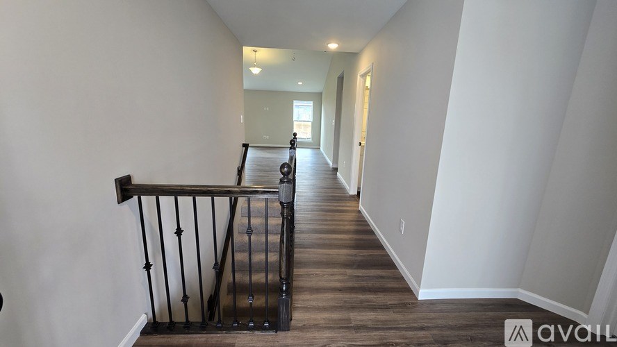 A hallway with a wooden floor and a metal railing.