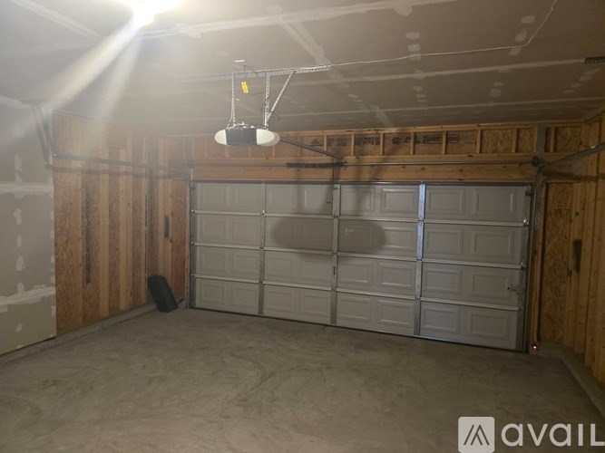 A garage with a white door and a black speaker hanging from the ceiling.