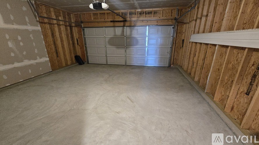 A spacious garage with a closed white door and wooden walls.