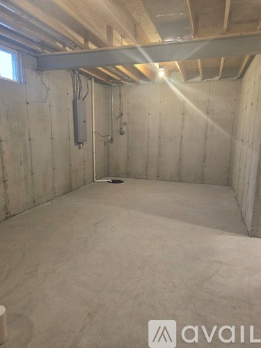 A room under construction with exposed ceiling beams and drywall.