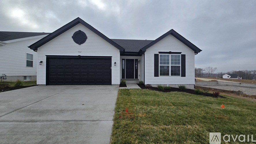 A white house with a black garage door is for sale.