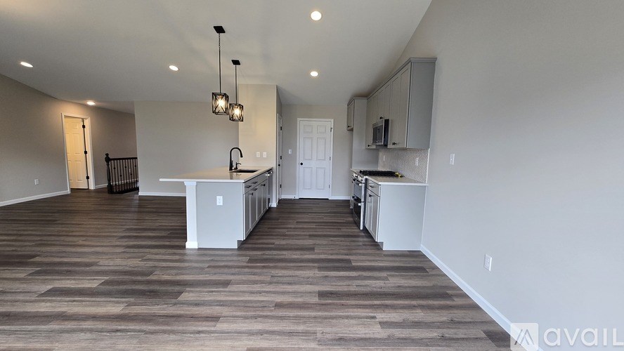 A spacious kitchen with white cabinets and a wooden floor.